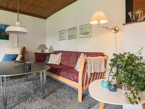 A cozy living room with a sofa, a round table, a lamp, and a potted plant. - 6 Person Holiday Home in Blavand (Blavand)