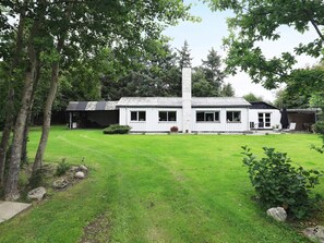 A white building with a tiled roof, a tall chimney, and a well-maintained lawn. - 6 Person Holiday Home in Blavand (Blavand)