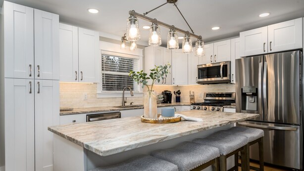 A modern kitchen with white cabinets, a stainless steel refrigerator, a built-in oven, and a marble island with bar stools. - 100% - 5 STAR reviews!   Legendary Getaway! (Township of Taylorsville)