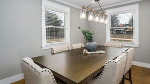 A dining room with a wooden table, beige upholstered chairs, a vase with a plant, and a hanging light fixture. - 100% - 5 STAR reviews!   Legendary Getaway! (Township of Taylorsville)