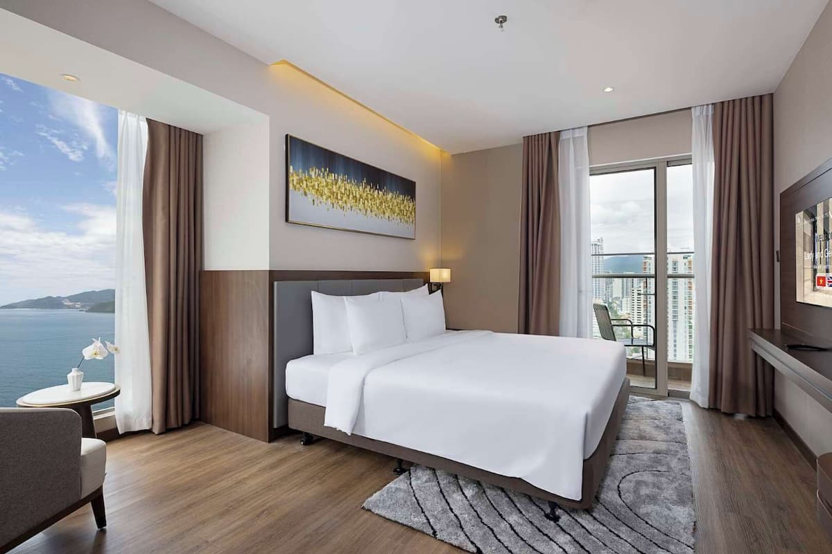 Habitación de hotel con una cama grande, televisión, escritorio y vista al mar.