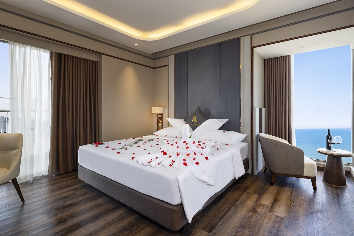 Habitación de hotel con una cama grande, un escritorio, una silla y vistas al océano.