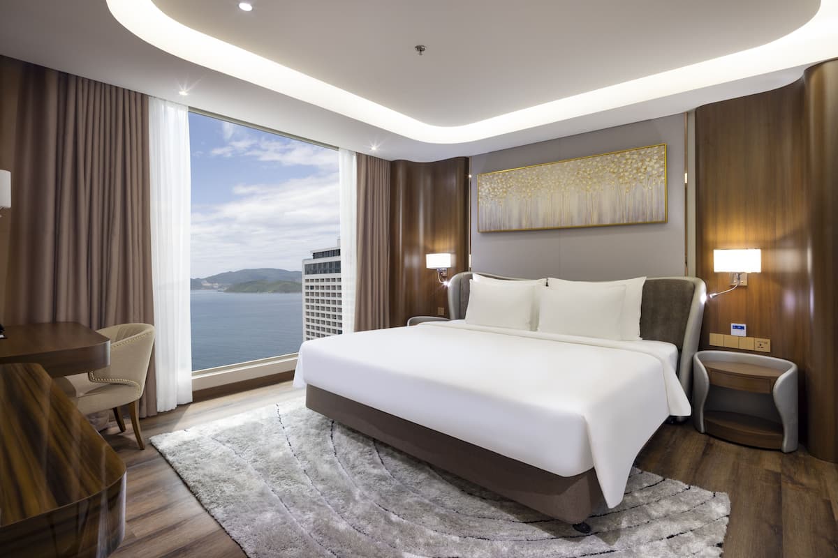 Un hotel moderno con una cama grande, un escritorio, una silla y vistas al mar.