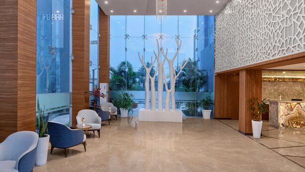 Un moderno vestíbulo con candelabro, zona de estar y mostrador de recepción.