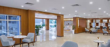 A spacious lobby with modern furniture, a reception desk, and a view of the outdoors.