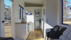 Una cocina compacta con ventana, un comedor con mesa y sillas, y vistas al exterior.