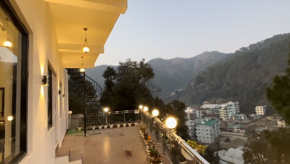 A balcony with a view of a mountainous landscape and nearby buildings. - Ramshila Cottage (Nainital)