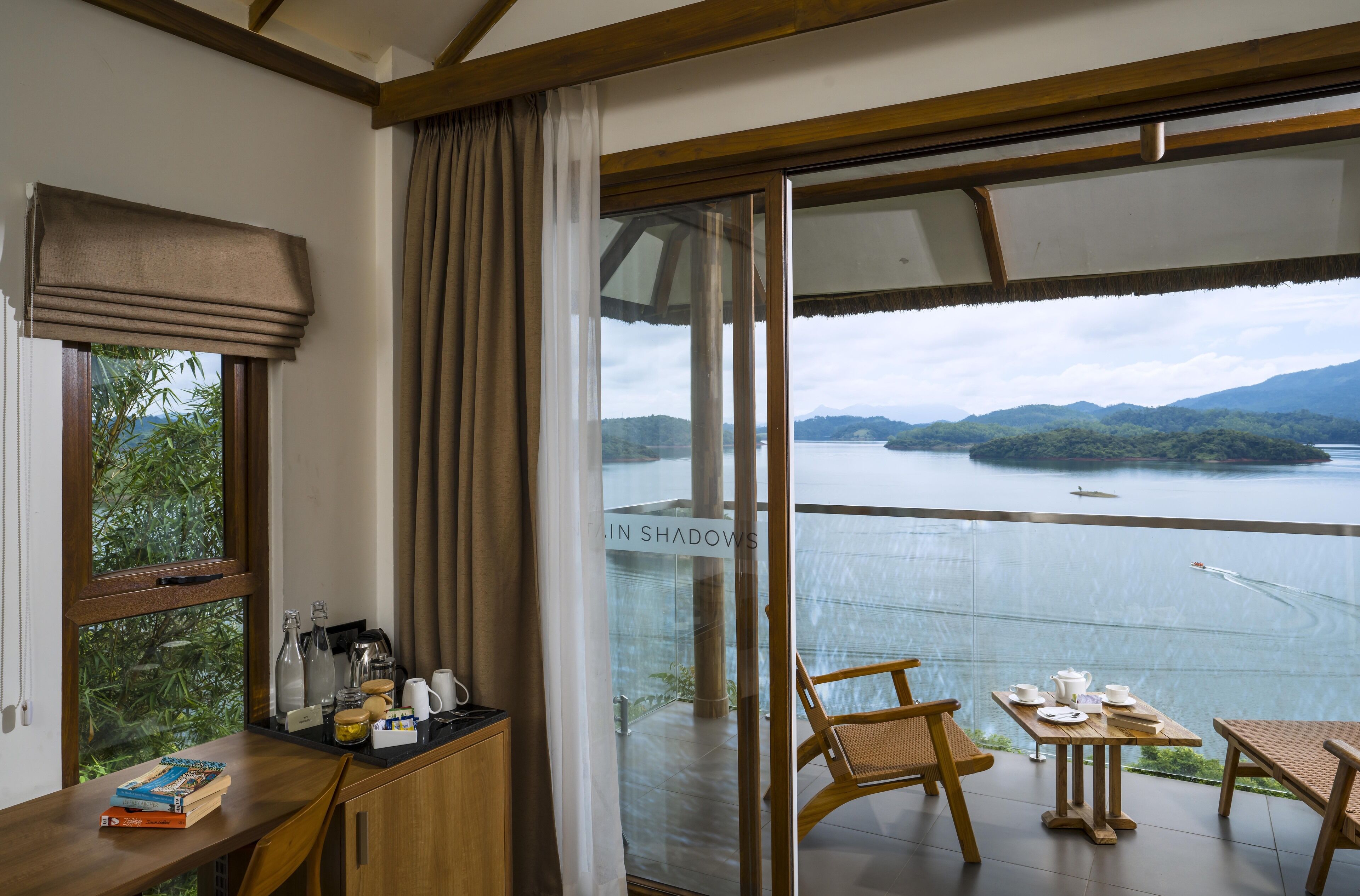 A balcony with a table set for dining, a view of a lake, and a sign reading "IN SHADOWS".