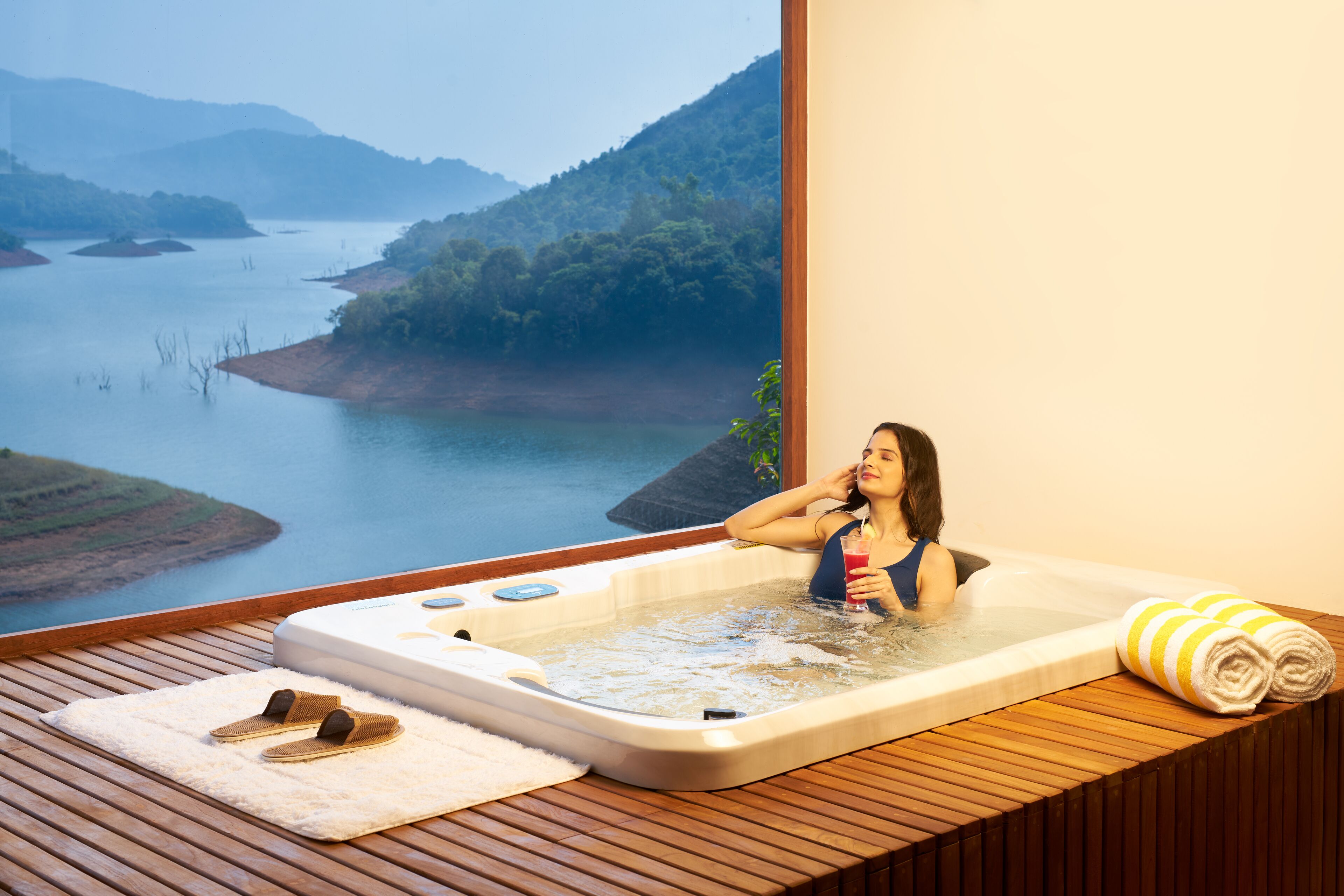A woman in a hot tub with a scenic view of a river and hills.