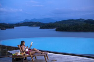 A woman relaxing on a wooden deck with a view of a calm lake and mountains in the background.