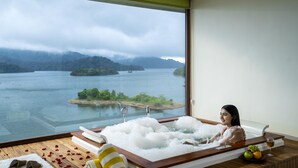 Una mujer se relaja en una bañera con vistas a un lago y montañas.
