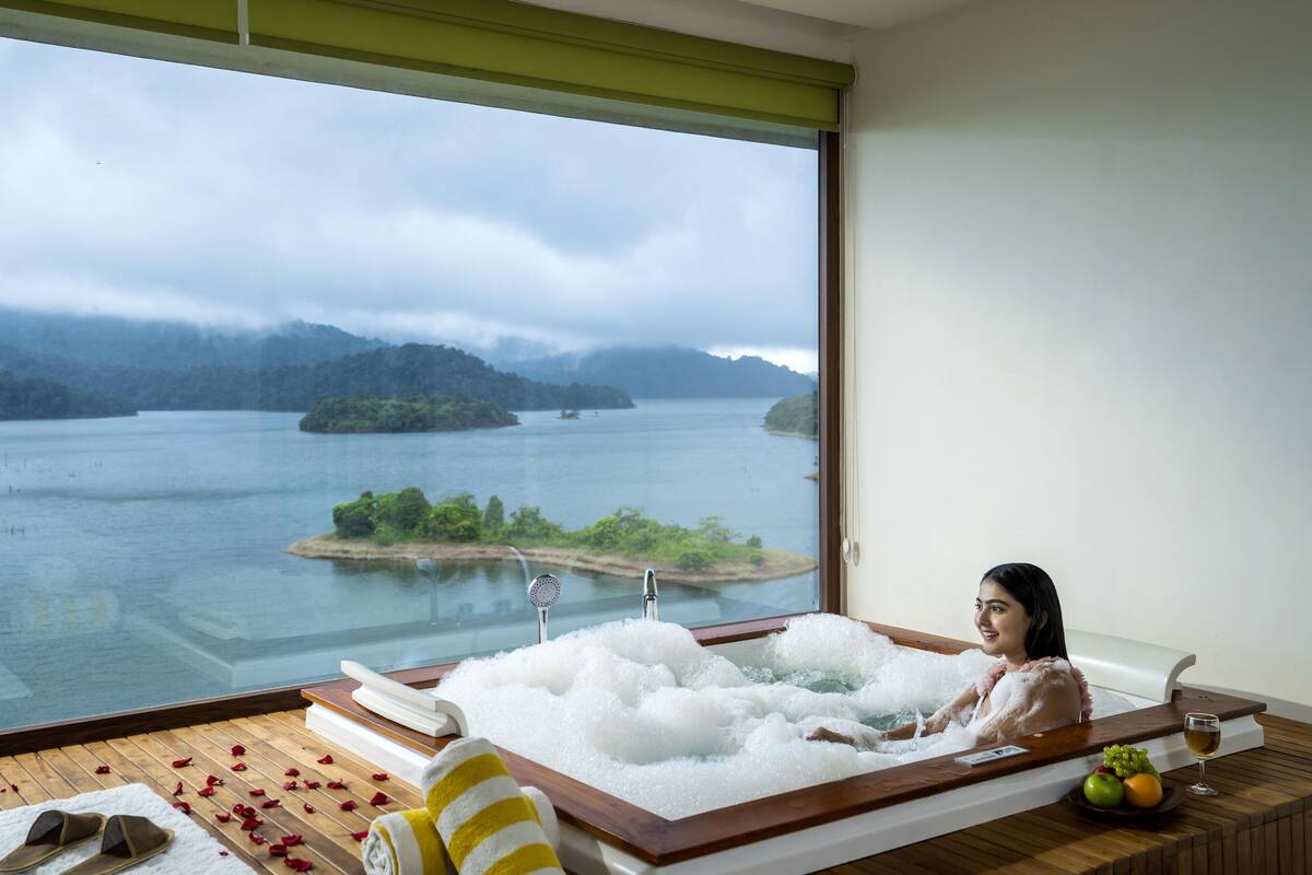 Mulher relaxando em uma banheira com vista para um lago e montanhas.