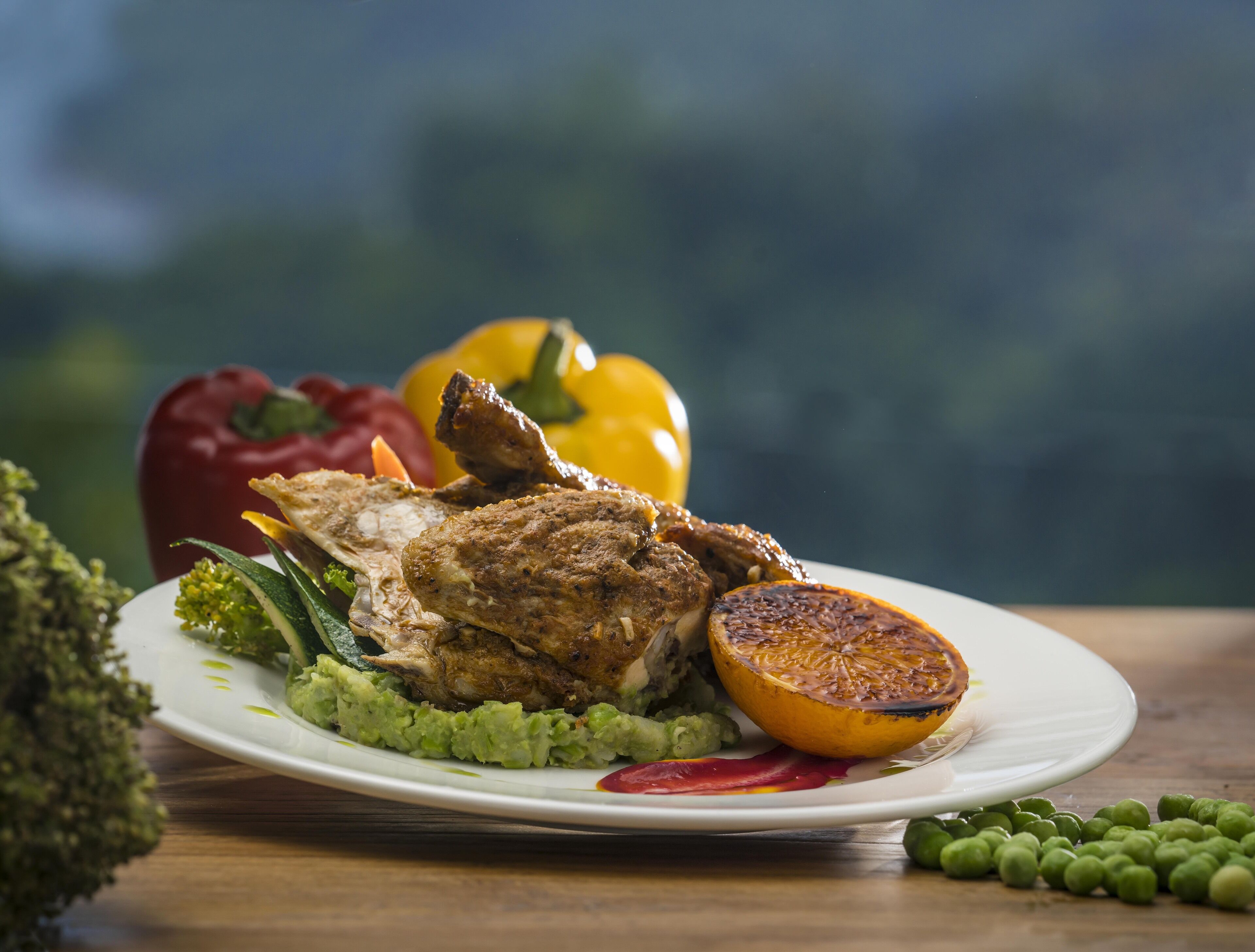 A plate of food with grilled meat, avocado, and a grilled orange slice.