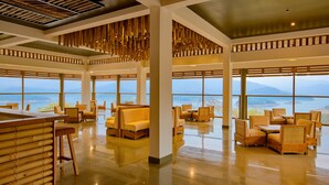 Un vestíbulo espacioso con techos altos, amplias ventanas que ofrecen vistas a las montañas y diversas opciones de asientos, incluyendo sofás y sillones.