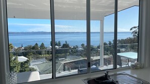 A kitchen with a large window overlooking a body of water and a view of buildings. - Spectacular water views & entertaining spaces (Corlette)