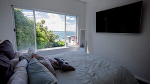 A bedroom with a large window, a bed, and a TV mounted on the wall. - Spectacular water views & entertaining spaces (Corlette)