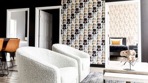A modern living room with a sofa, a coffee table, and a patterned wallpaper.