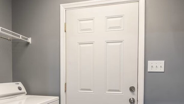 Un cuarto de lavado con una puerta blanca, una lavadora y una secadora.