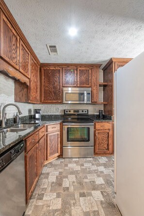 A kitchen with wooden cabinets, a stainless steel oven, and a microwave. - Charming, Convenient 3-bedroom Garden Home in Prattville; Great Location (Prattville)