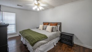 Un dormitorio con cama, mesita de noche, cómoda y ventilador de techo.