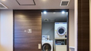 A hotel room with a wooden table, a chair, a washing machine, and a dryer. - Hotel Plus Hostel TOKYO AKIHABARA (Tokyo)