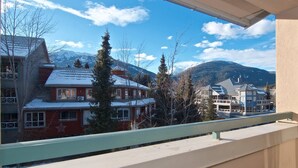 A view from a balcony overlooking a snowy mountain landscape with buildings and trees. - Eagle Lodge Village 2 bedroom condo, steps to Village, shops and restaurants (Whistler)