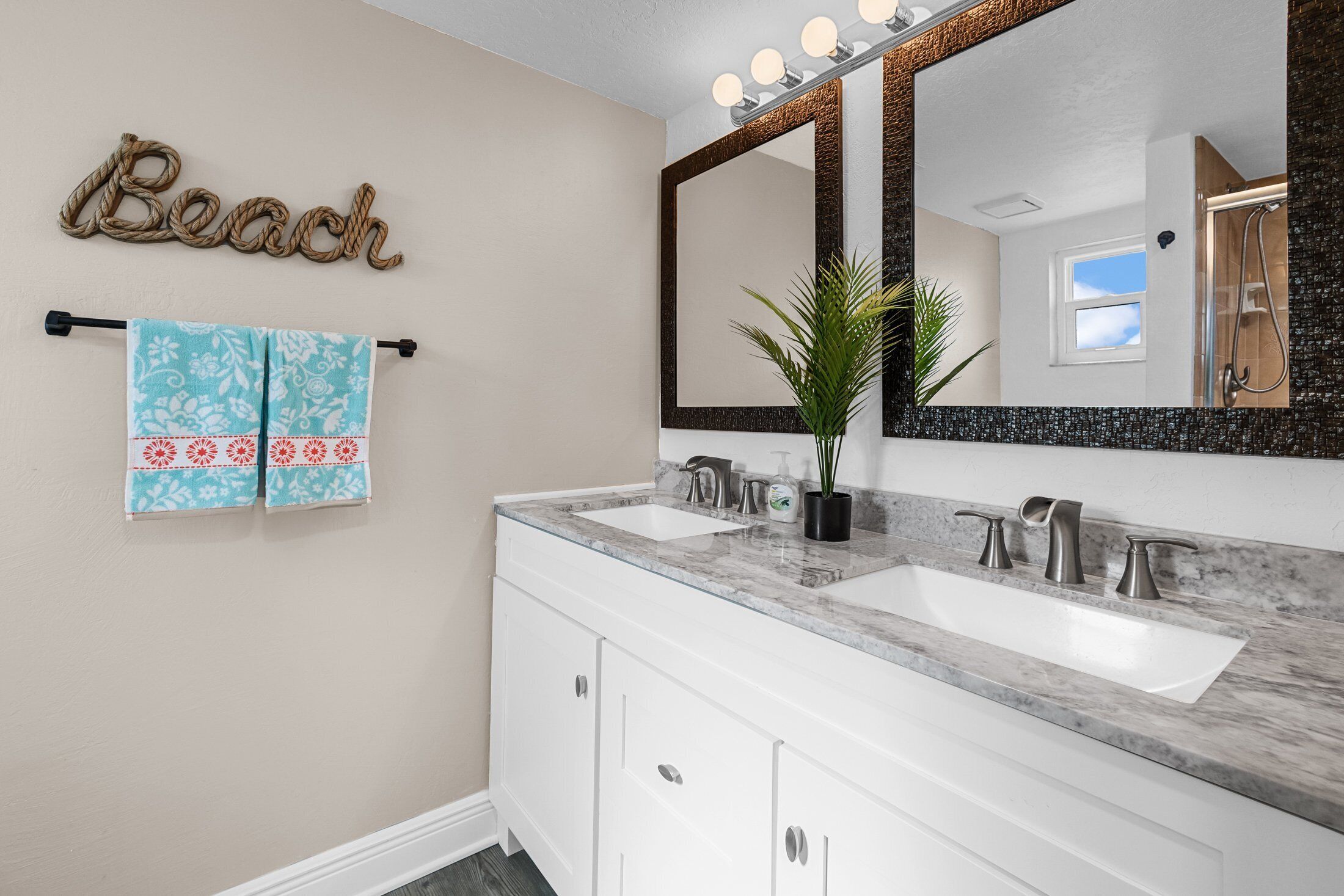 A bathroom with two sinks, a large mirror, and a towel rack with patterned towels.