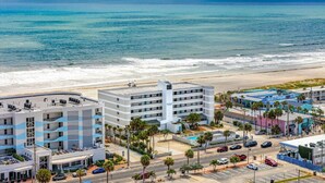 Un hotel costero con varias edificaciones, una playa y una carretera con coches.