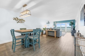 A spacious living area with a dining table, chairs, and a sofa. - Boardwalk 205 (Cocoa Beach)