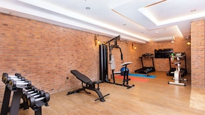 Uma academia com equipamentos de ginástica, um banco e uma televisão presa à parede.