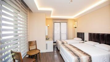 Una habitación de hotel con cama, escritorio, silla y ventana con persianas.
