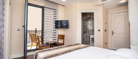 A hotel room with a bed, a television, a door, and a balcony with a chair and table.