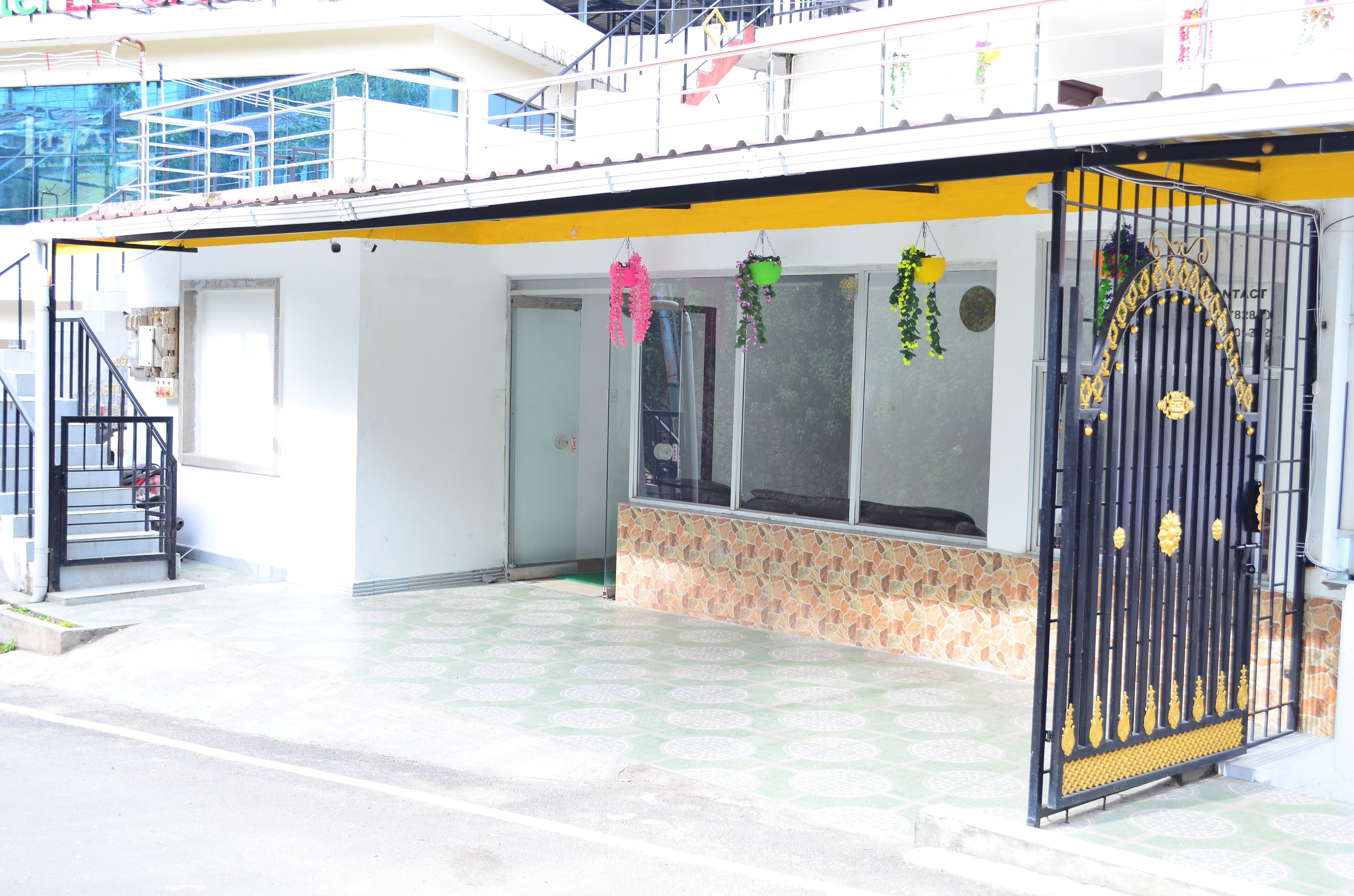 A building with a gated entrance, a staircase, and a covered area with patterned flooring.