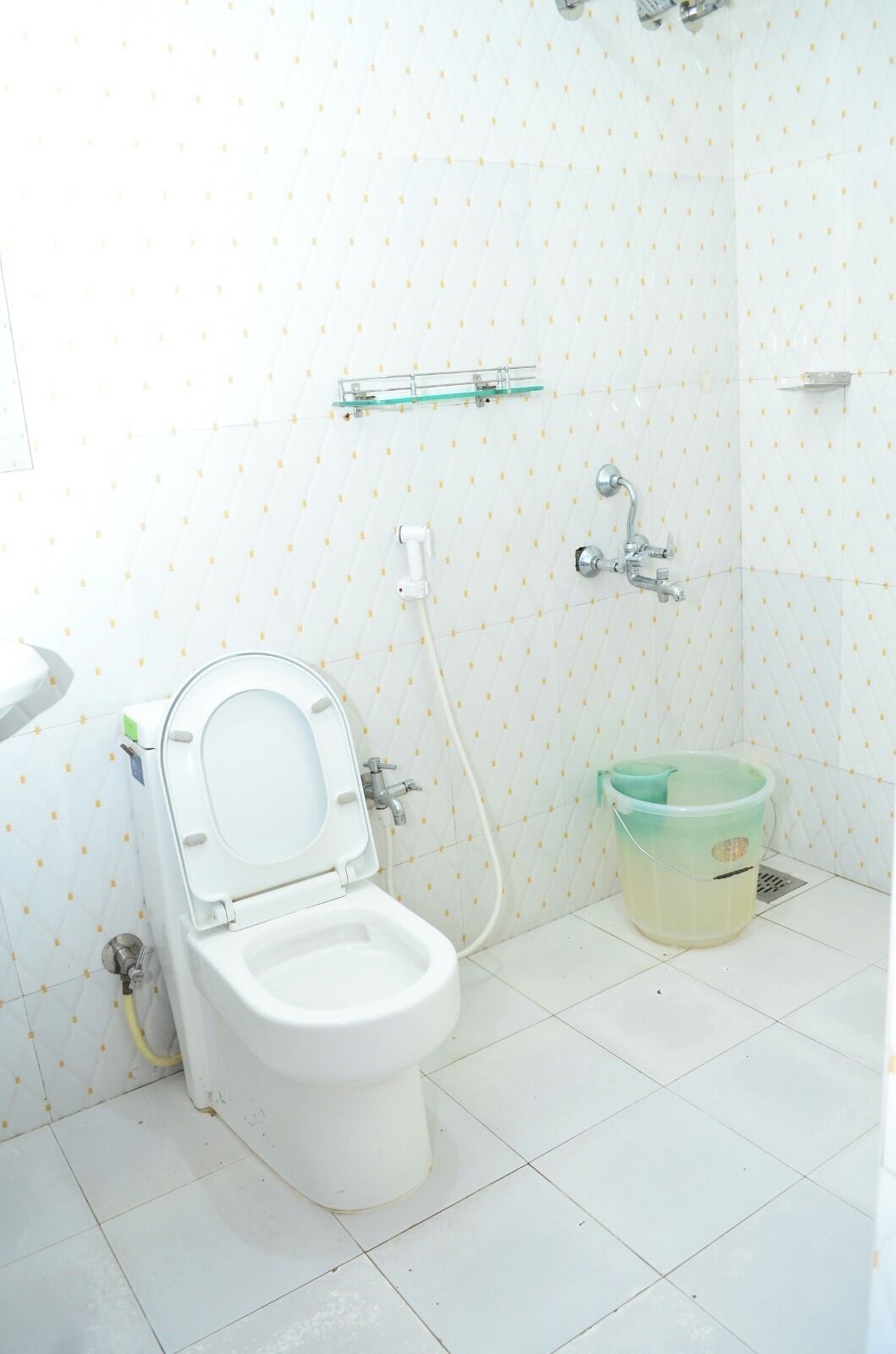 Egy fürdőszoba, amelyben WC, zuhanyzó és vödör található.