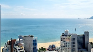 A coastal cityscape with a beach, high-rise buildings, and a clear sky.