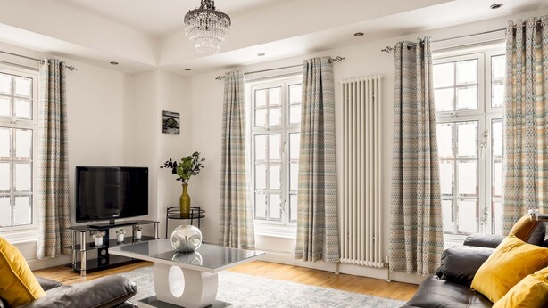 A modern living room with a flat-screen TV, a glass coffee table, leather sofas, and patterned curtains. - Mayfair Park Lane Lux 2-bedroom Apartment (London)