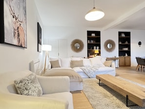 A modern living room with a sofa, coffee table, and a dining area with a table and chairs. - Au coeur de ville, bel appt 3 chambres de 105m2. (Cauterets)