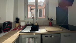 Una cocina con ventana, una cafetera Bosch, un fregadero, una tabla de cortar y un lavavajillas.