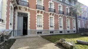 Un edificio con fachada roja, detalles blancos y múltiples ventanas con balcones de hierro forjado.