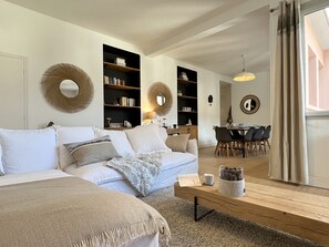 Een moderne woonkamer met een bank, salontafel en een eethoek.