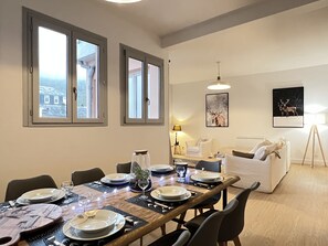 A dining area with a table set for four, a sofa, and a lamp. - Au coeur de ville, bel appt 3 chambres de 105m2. (Cauterets)