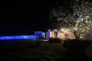 A house with a well-lit entrance, a covered outdoor area, and a tree in the foreground.