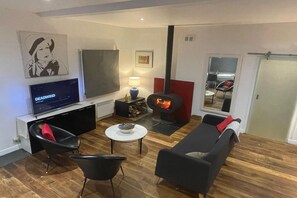 A modern living room with a flat-screen TV, a fireplace, and a sofa.