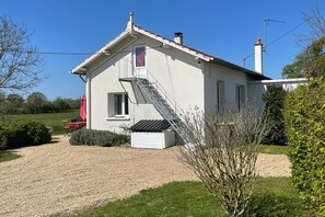 A single-story house with a visible garage door, a staircase leading to the entrance, and a gravel driveway.