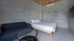 A modern bedroom with a bed, a blue sofa, and a glass table. - sunisland (Liuqiu)