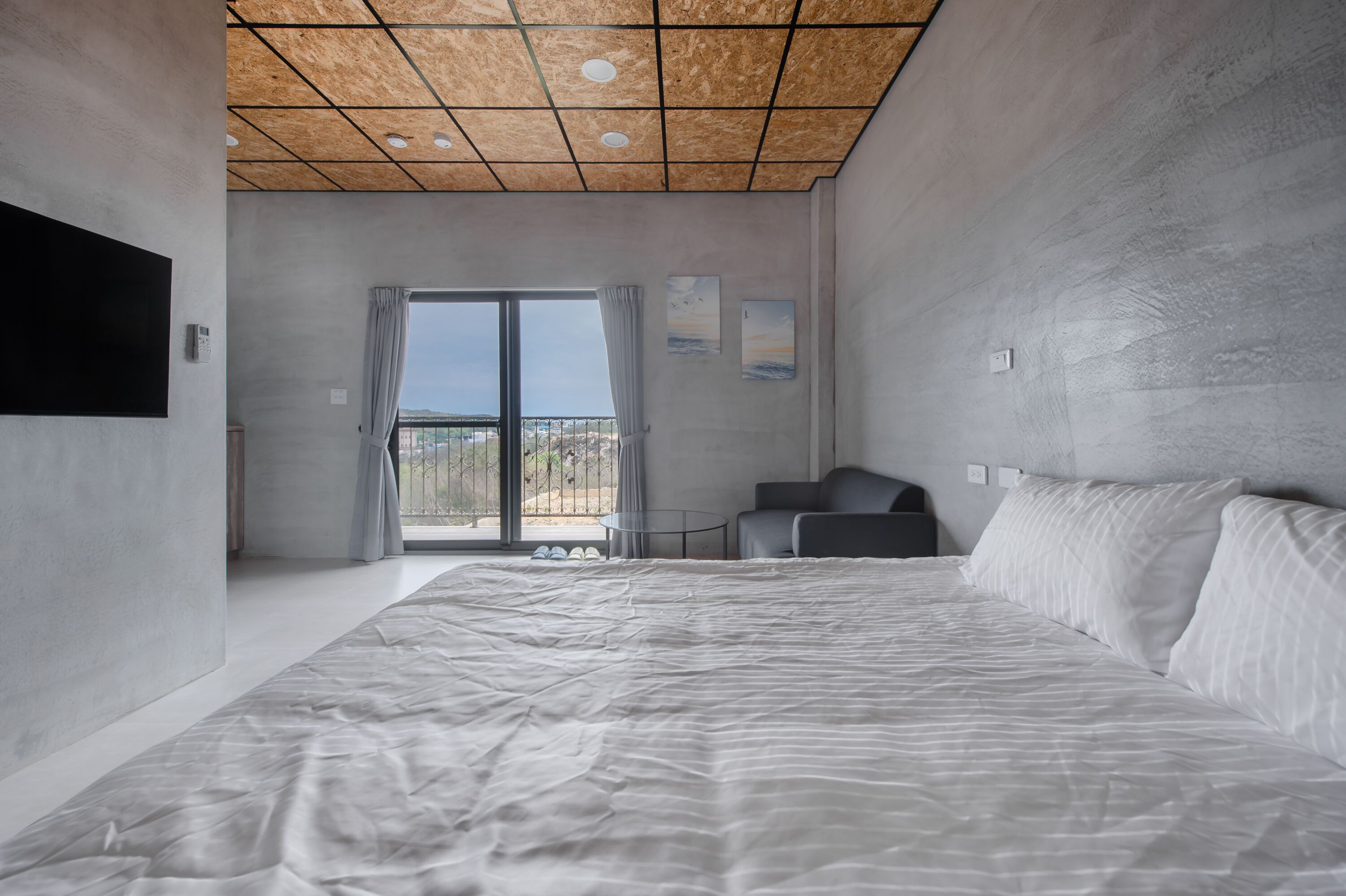 Un dormitorio moderno con una cama grande, una mesita pequeña y un sofá.