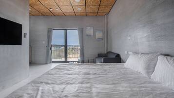 Un dormitorio moderno con una cama grande, una mesita pequeña y un sofá.