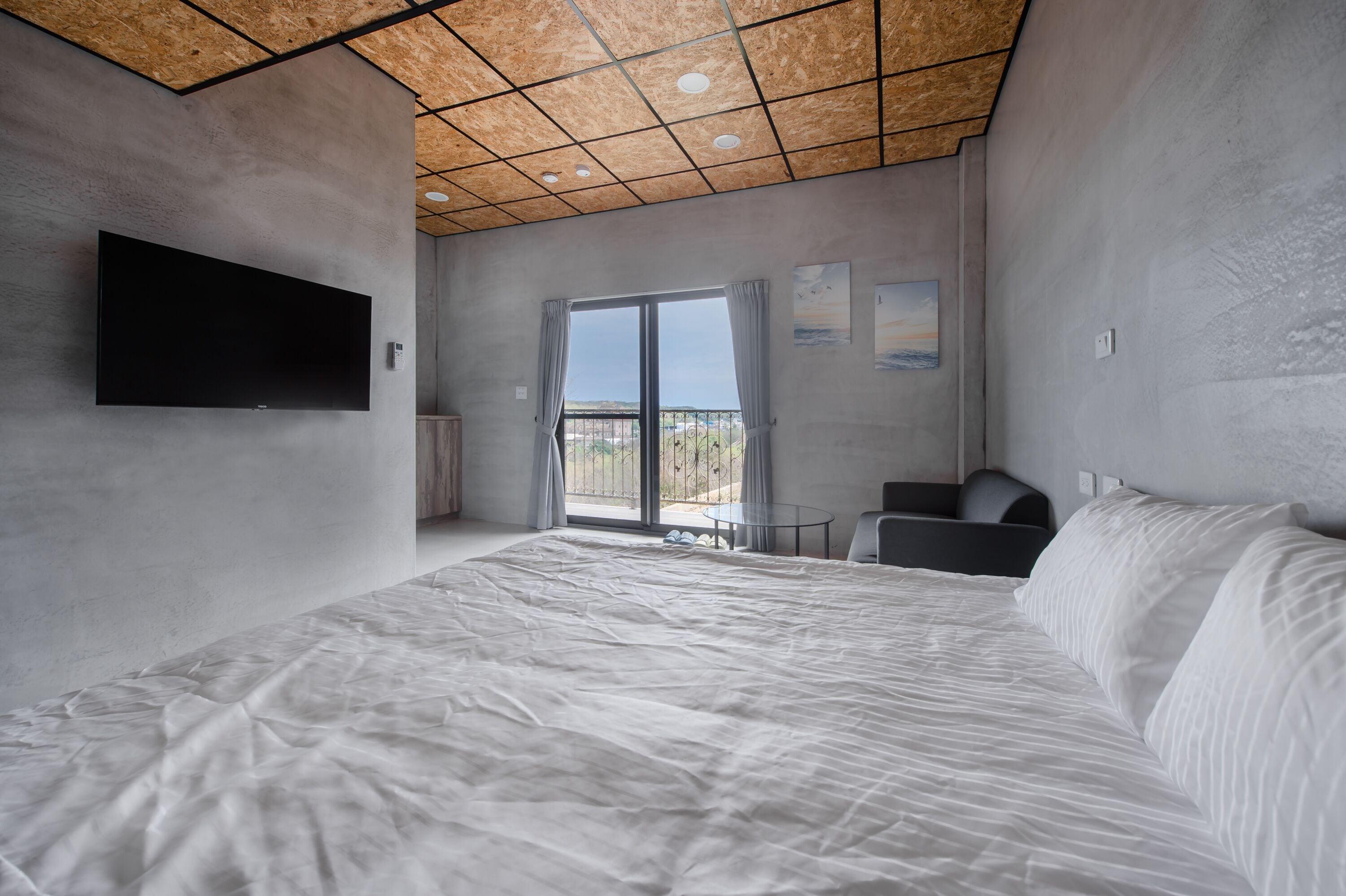 Ein modernes Schlafzimmer mit einem großen Bett, einem Flachbildfernseher und einem Balkon mit Blick.