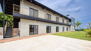 A modern building with a flat roof, large windows, and a covered outdoor area with a concrete floor and a grassy lawn. - sunisland (Liuqiu)