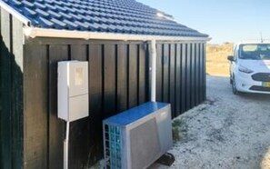 Un bâtiment doté d’un toit en pente, d’un coffret électrique et d’un appareil de climatisation.